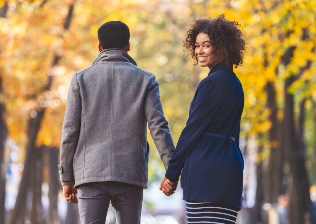 Casal de mãos dadas mulher olhando para trás e sorrindo