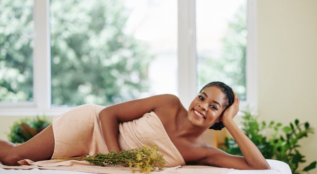 Uma mulher de toalha deitada em uma cama de spa.